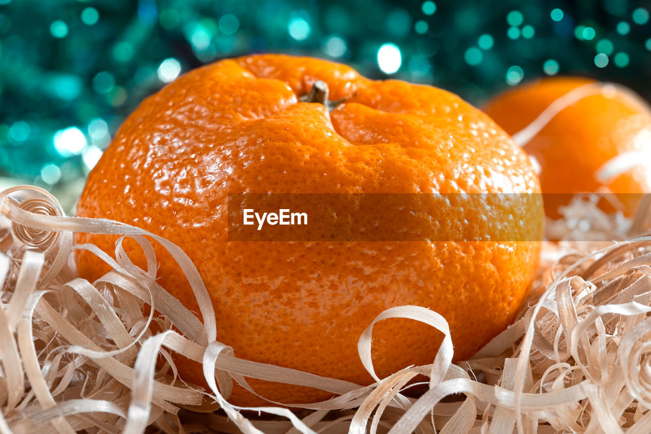 Ripe orange tangerine, not peeled, on a bright blurred background with bokeh. 