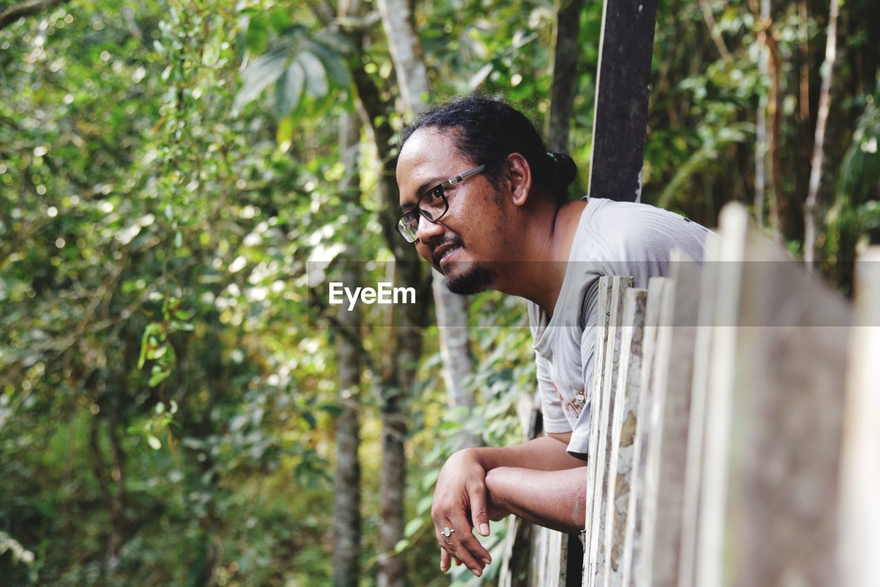 Side view of young man looking away in forest