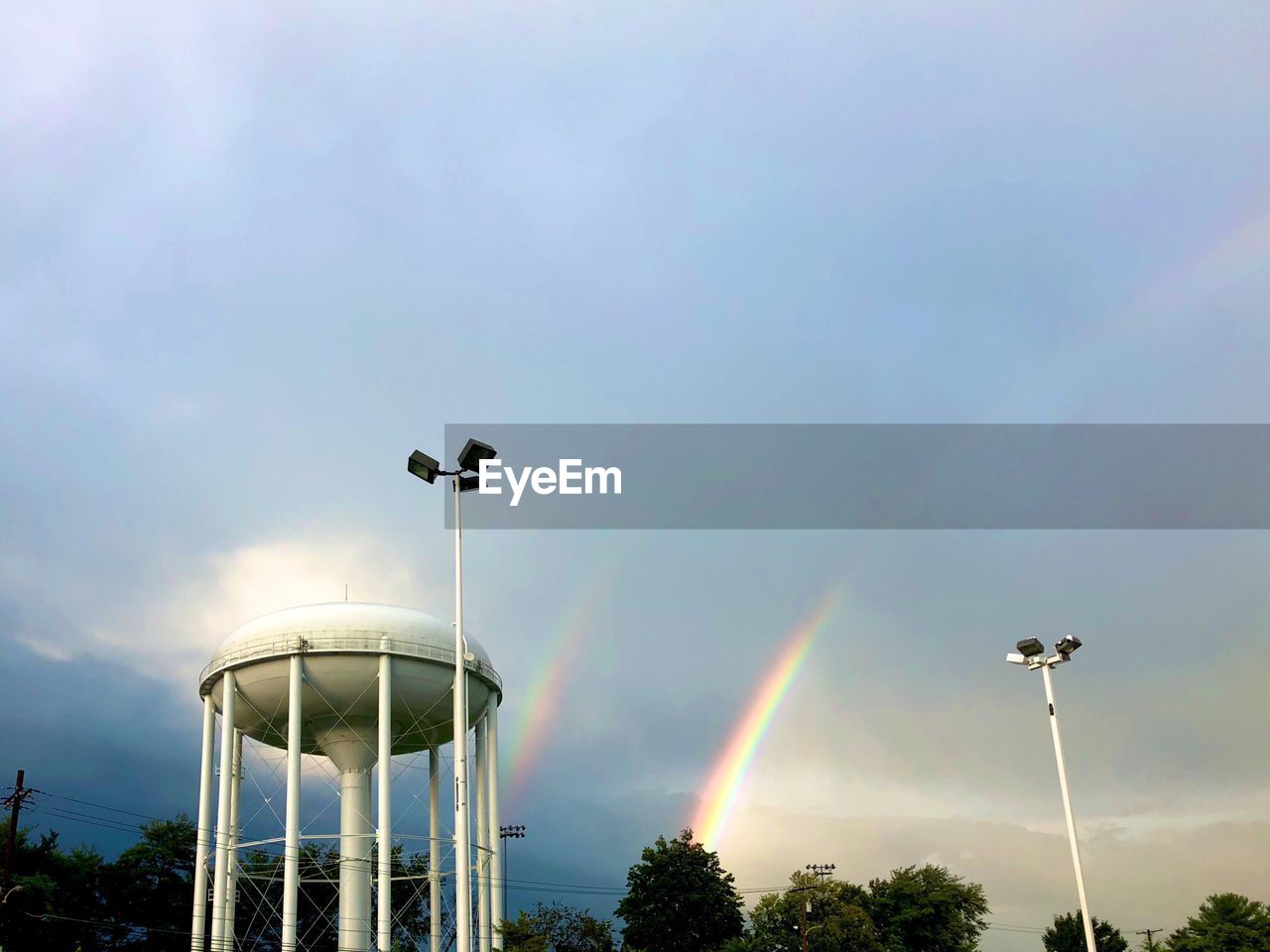 LOW ANGLE VIEW OF STREET LIGHT AGAINST RAINBOW