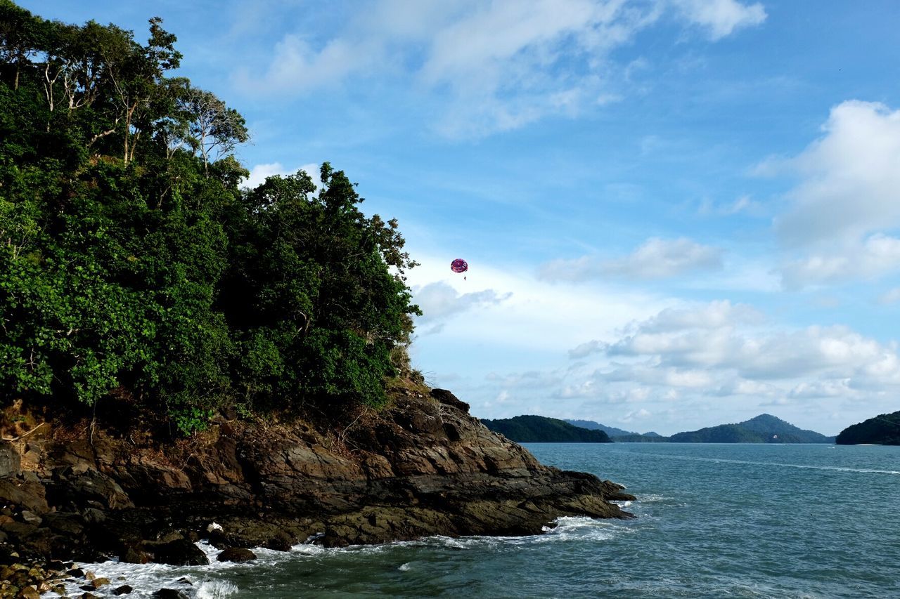 Distant view of person parasailing against sky