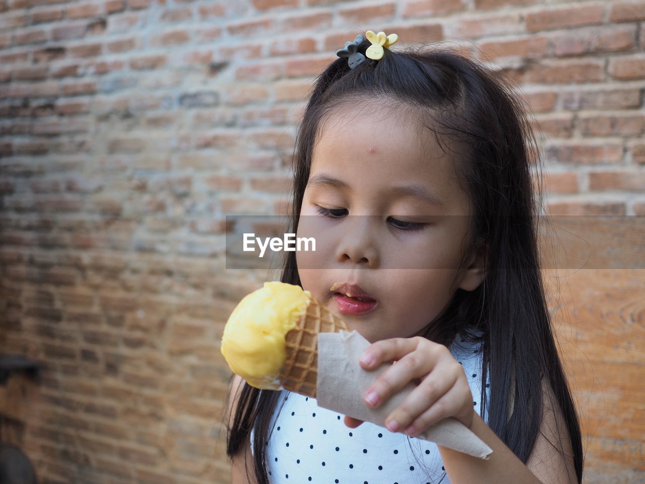 Portrait of girl holding ice cream against wall