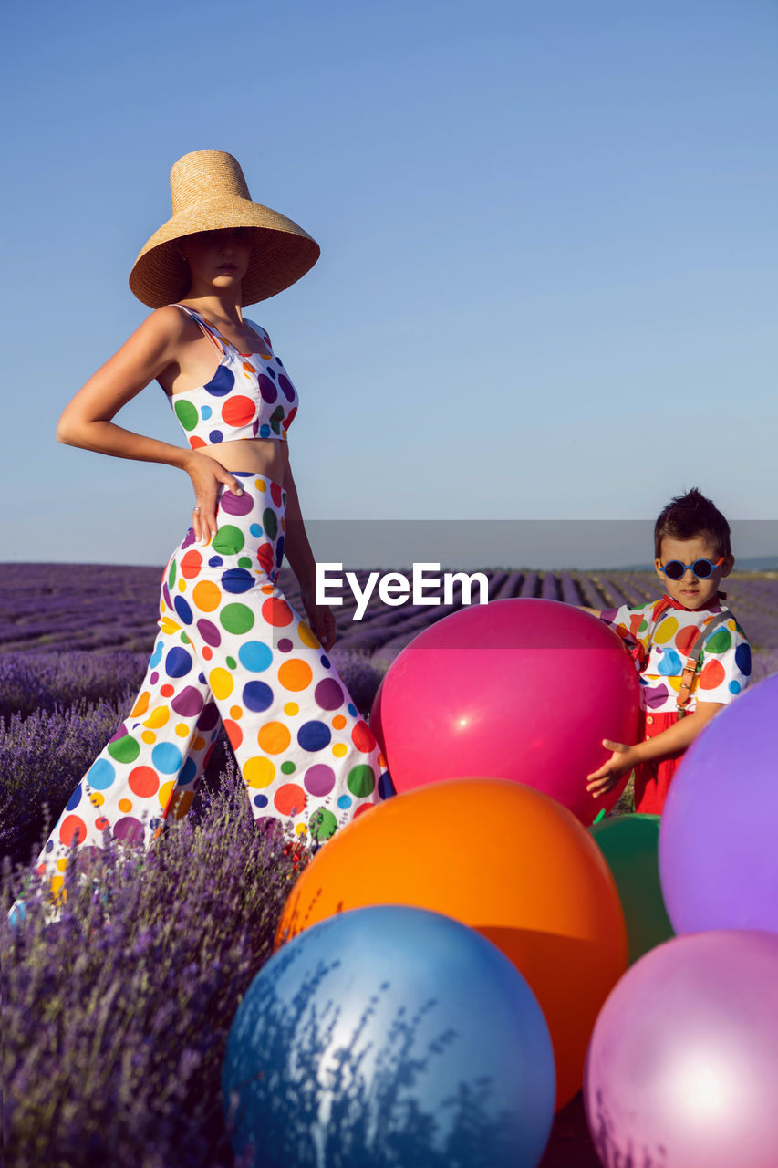 Rear view of woman with balloons against sky