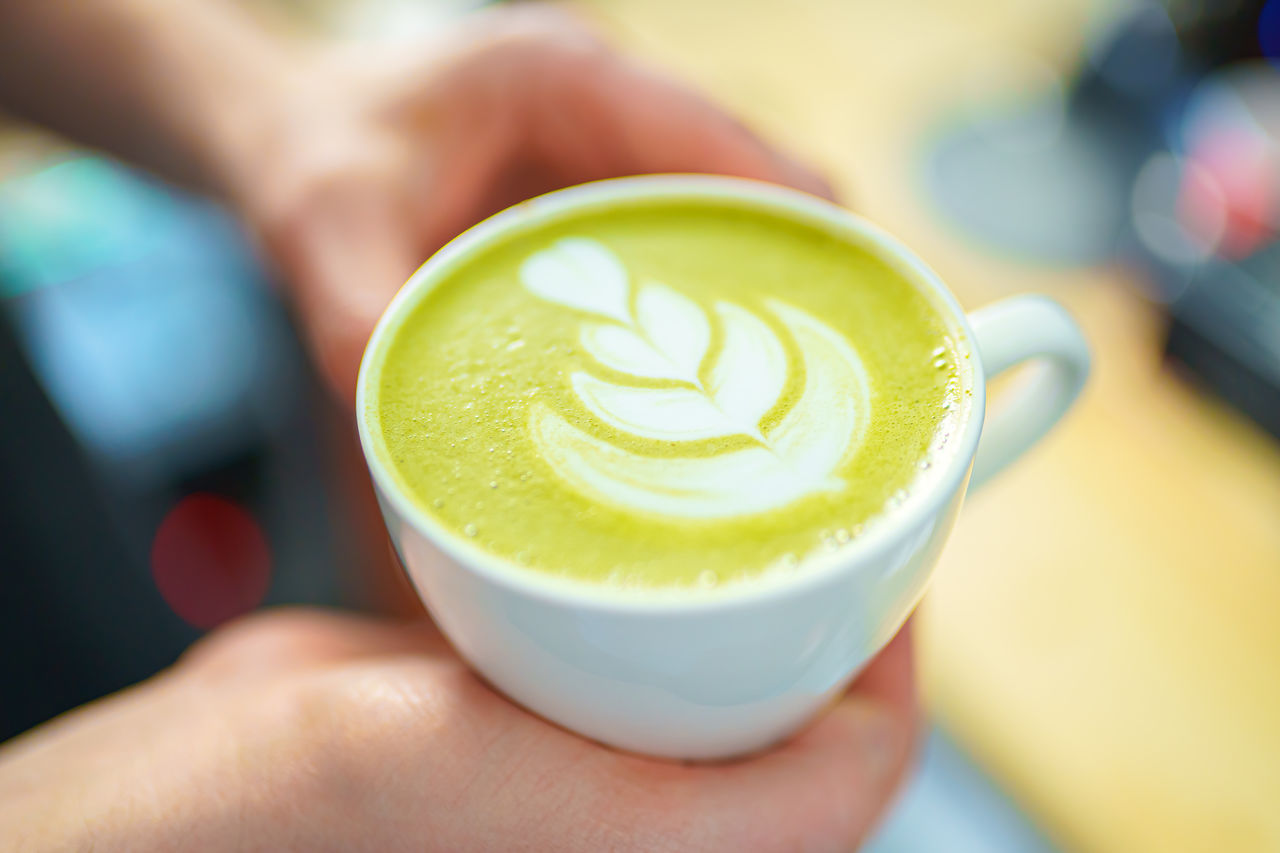 Barista holding a cup of matcha latte in her hands