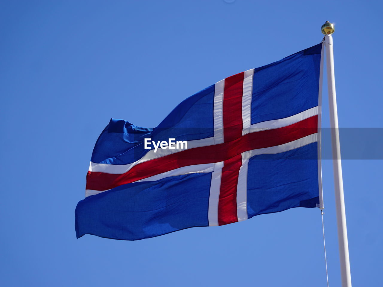 Low angle view of icelandic flag against clear blue sky