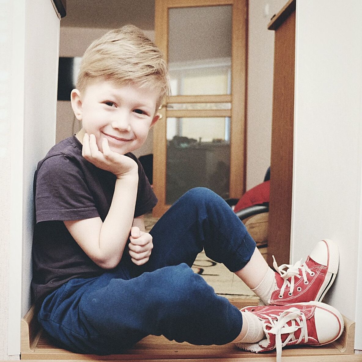 Portrait of smiling boy sitting by wall on floor