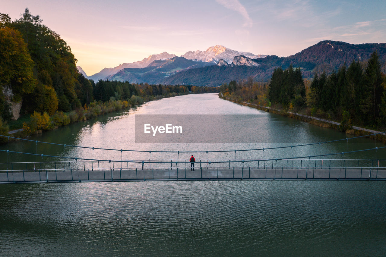 Aerial view of man standing on bridge over salzach river at sunset, salzburg, austria.