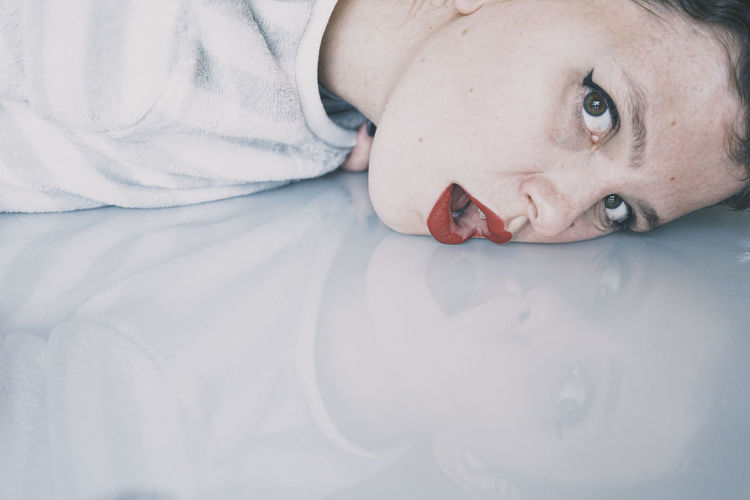 Close-up portrait of woman lying down mouth open