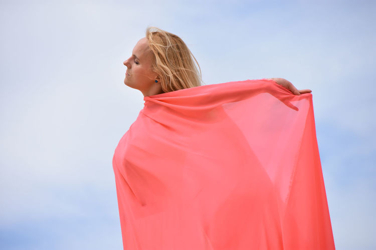 Midsection of woman with red umbrella against sky