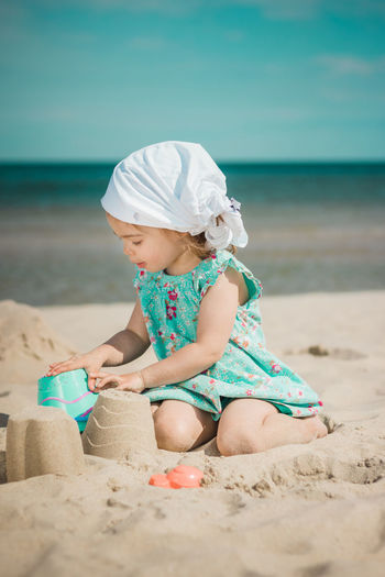 Full length of girl making sandcastles while sitting on beach