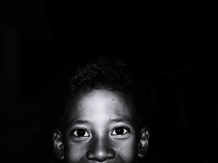Close-up portrait of boy against black background