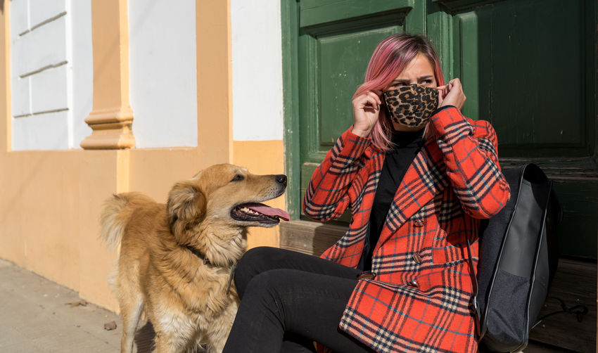 Close-up of woman wearing mask sitting by dog
