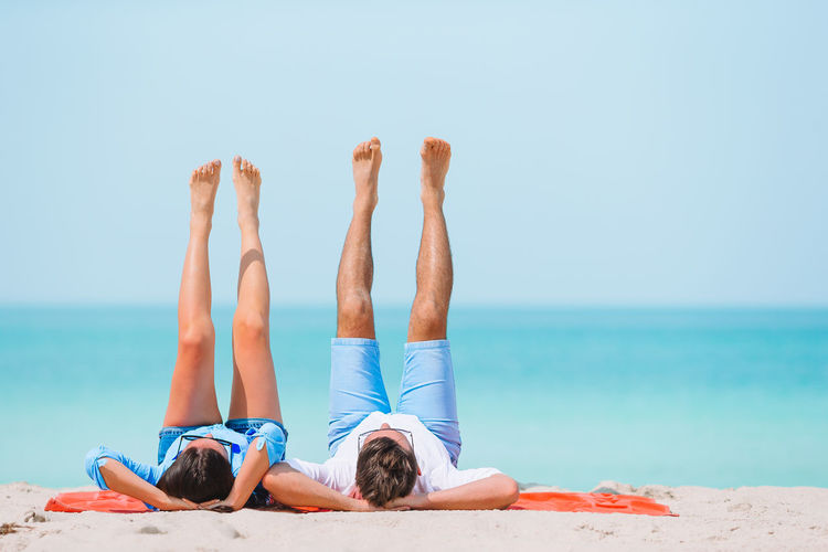 Couple with feet up while lying on beach