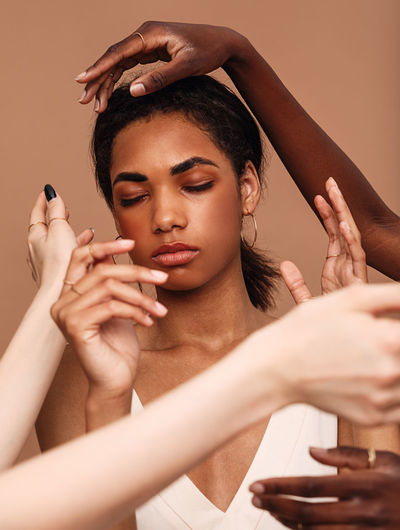 Beautiful woman amid multi-ethnic hands against brown background