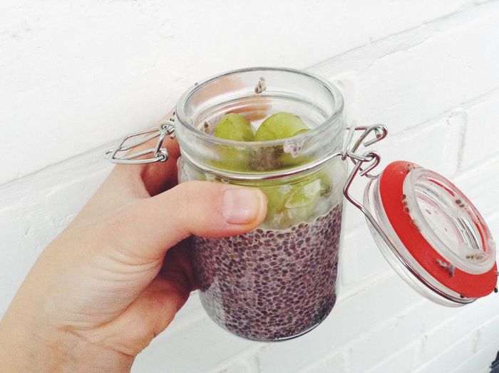 Cropped image of hand holding gooseberry and chia seeds in jar