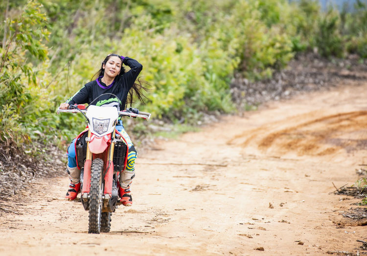 Woman riding her dirt-bike on forest track in pak chong / thailand