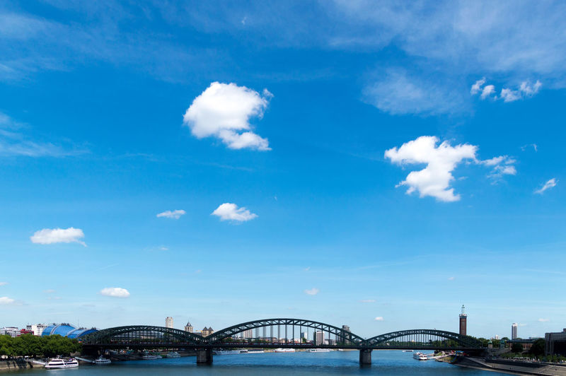 Bridge over river in city against blue sky