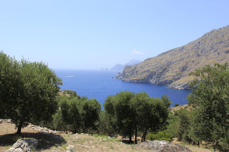 Scenic view of sea and mountains against clear blue sky