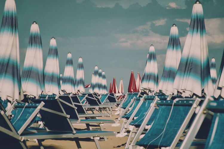 Panoramic view of long chairs and beach umbrellas against sky