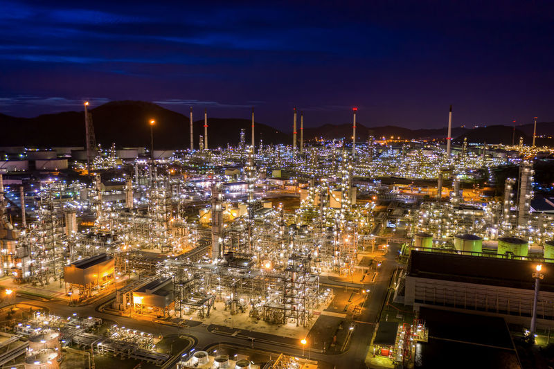 High angle view refinery area of illuminated cityscape against sky at night