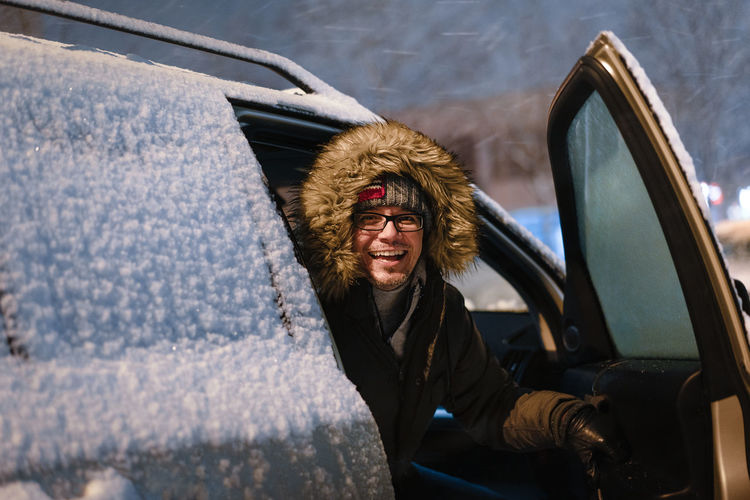 Portrait of man sitting in car in snow during blizzard