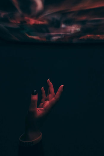 Close-up of woman hand against sea at night