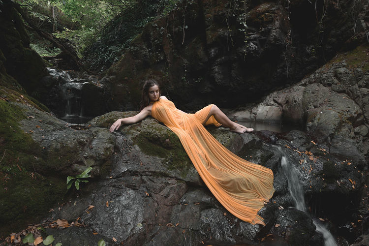 Woman in orange dress lying on rocks