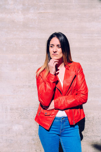Beautiful woman standing against wall during sunny day