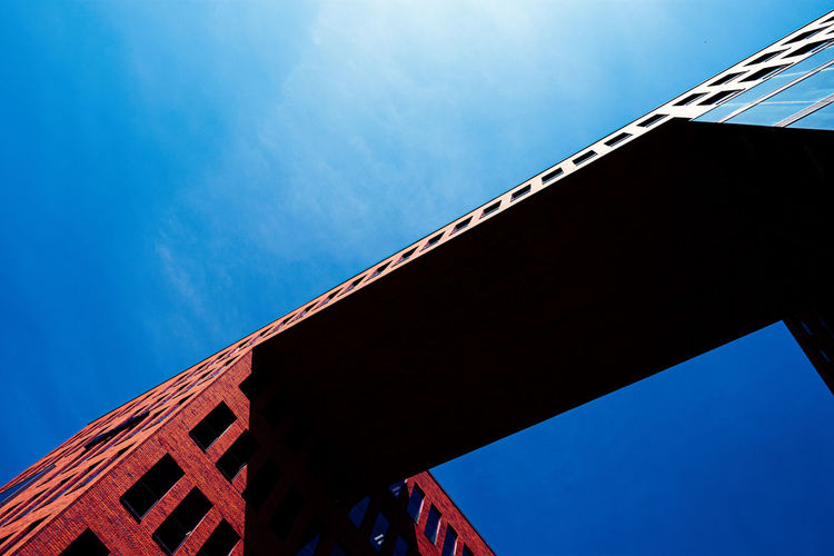 Low angle view of bridge by building against sky