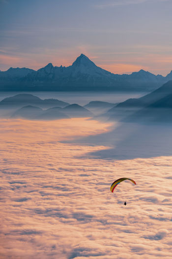 Silhouette of person paragliding over cloudscape