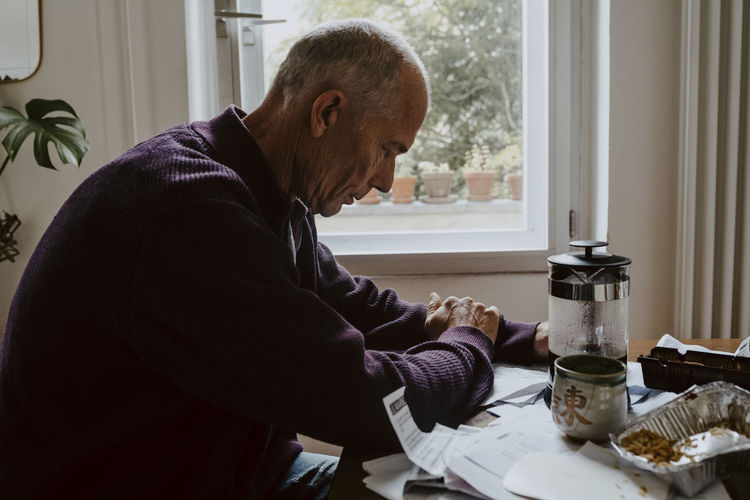 Worried senior man looking down at home