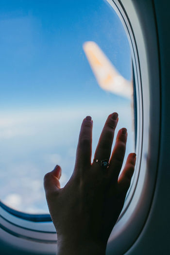 Beautiful women's hands with a ring, and an airplane window view of sky and wing of the plane.