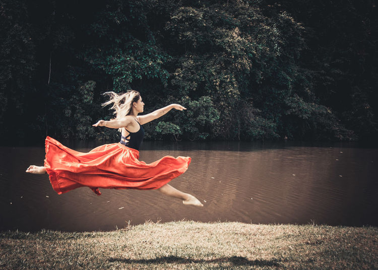 Young ballet dancer wearing red skirt while dancing in forest