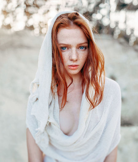 Portrait of beautiful teenage girl wearing white scarf standing on field