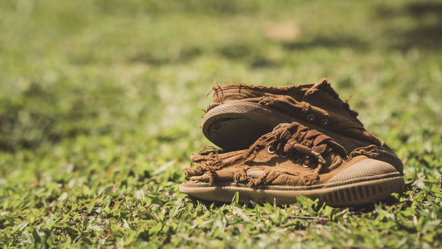 Close-up of torn shoes on field