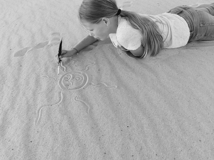 High angle view of girl playing with sand at sandy beach