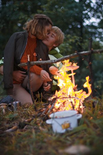 Romantic couple roasting mushrooms in forest