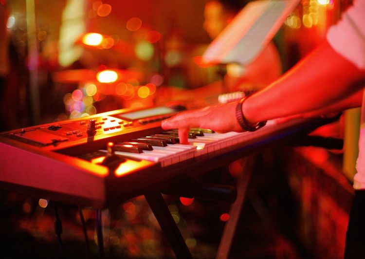 Cropped hands of man playing piano in nightclub