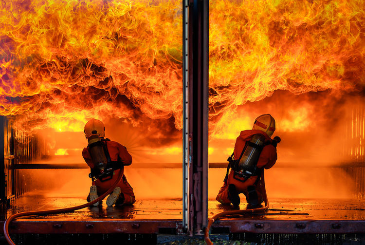 Men with fire hydrant against orange sky