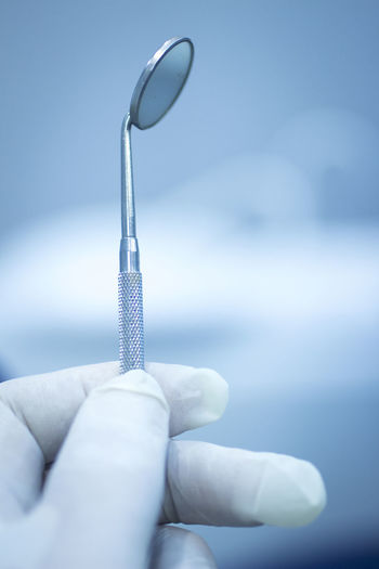 Cropped hand of dentist holding dental equipment in medical clinic