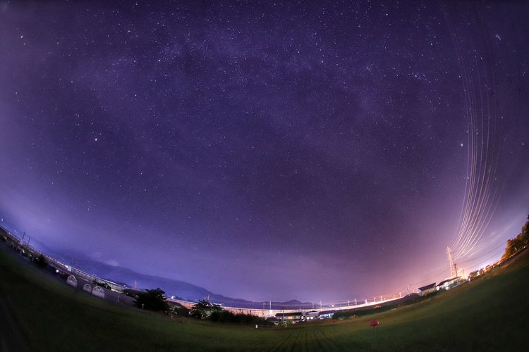 Fish-eye view of field against sky at night