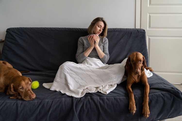 Woman with dog sitting on sofa at home