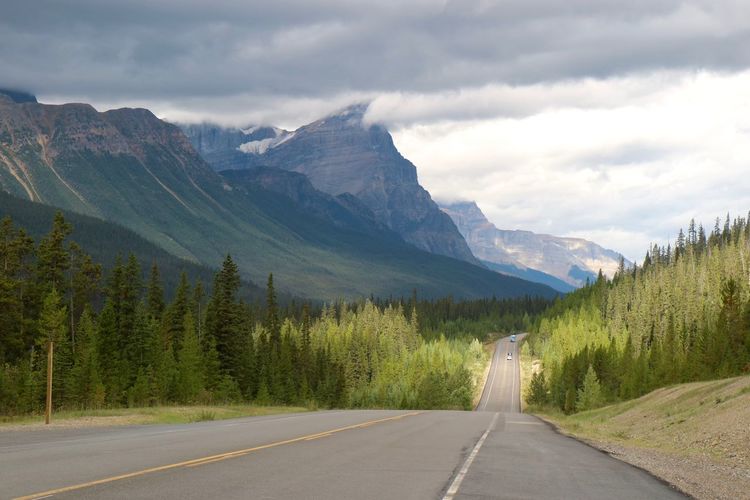 Road by mountains against sky