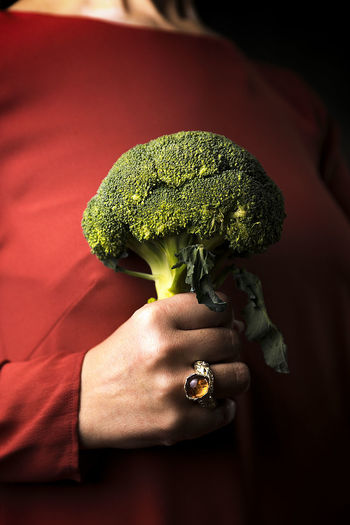 Woman in a tile-colored dress, and broccoli in hand