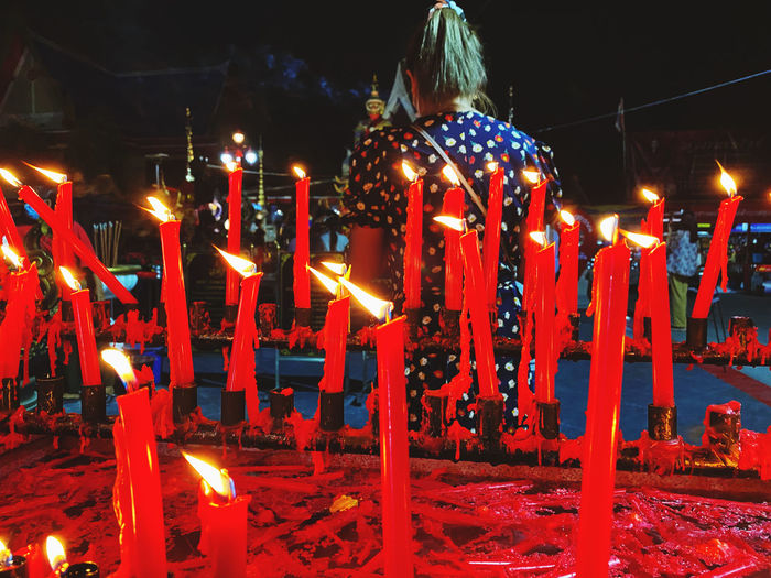 Illuminated candles against temple at night