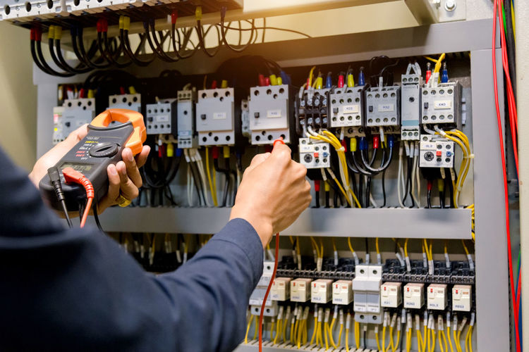 Midsection of man checking electrical equipment