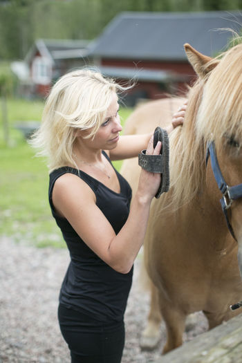Young woman brushing horse