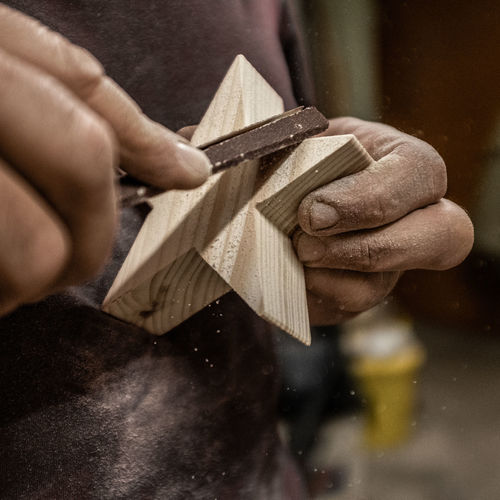 Midsection of carpenter making wooden star shape