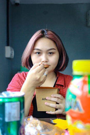 Portrait of young woman eating food at cafe