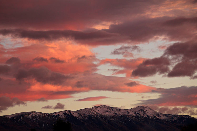 Scenic view of snowcapped mountains against orange sky