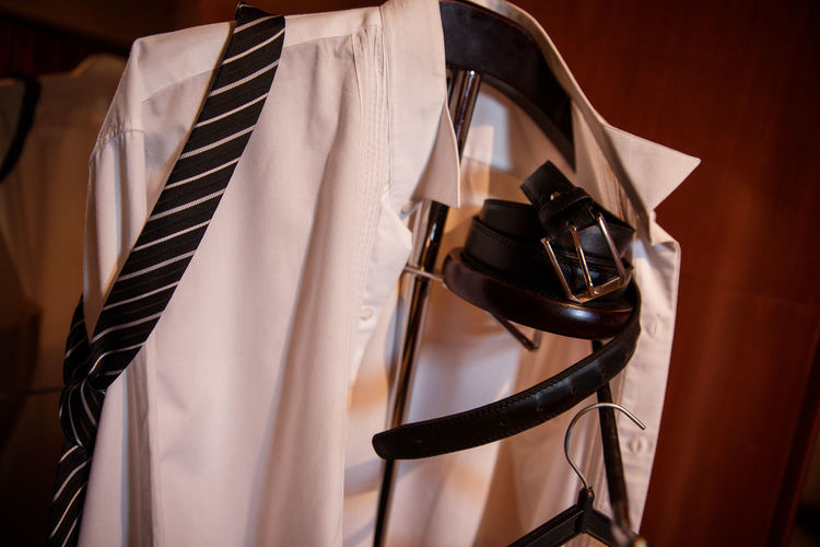Close-up of necktie and shirt with belt on coathanger